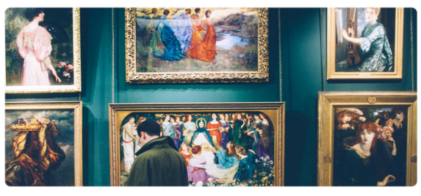 Student standing in front of a wall of paintings in a gallery