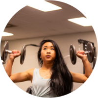 A female student lifts weights in the gym.